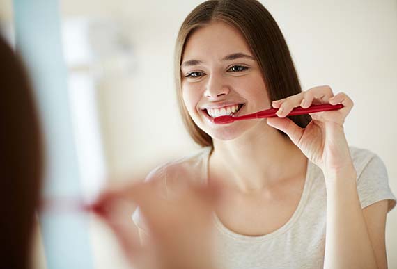 woman brushing her teeth woman brushing her teeth that were recently cleaned by a dental hygienist