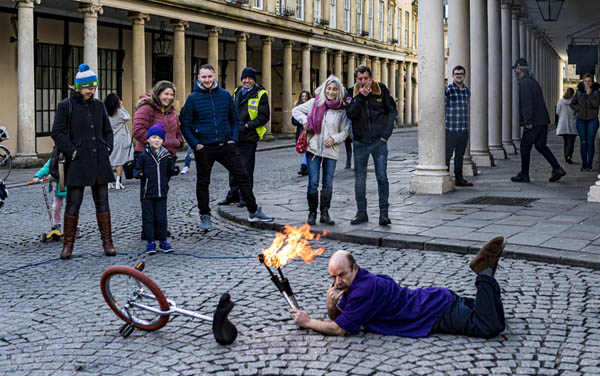 unicycle man on ground next to his unicycle holding fire