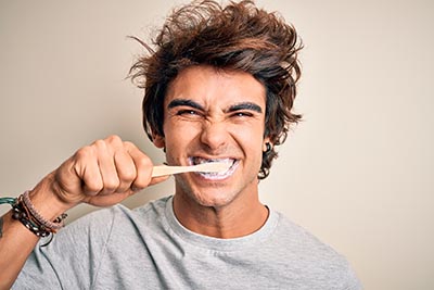 Young handsome man smiling happy. Standing with smile on face whasing tooth using toothbrush over isolated white background handsome young man brushing his white teeth